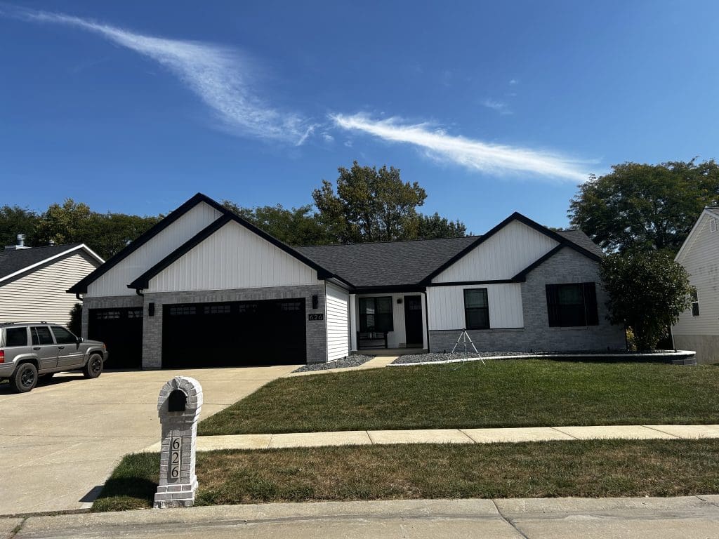 St. Louis single-story home with black roof, updated siding, three-car garage, and silver SUV—ideal for roofing or gutter services.