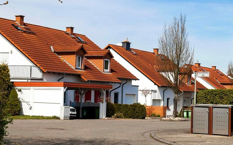 Modern homes with red tile roofs and white siding line a peaceful street in Greater St. Louis under a clear sky.