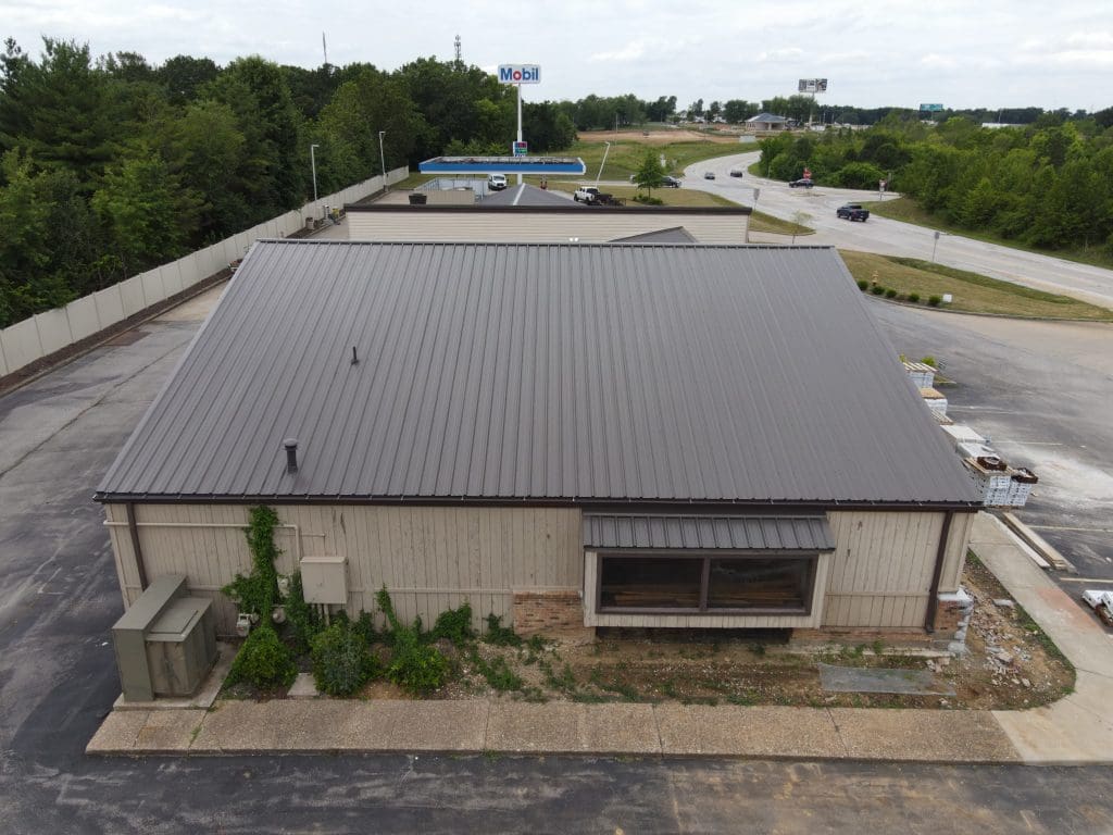 Commercial building in Greater St. Louis with metal roof and beige siding, near Mobil gas station—ideal for roofing or siding updates.