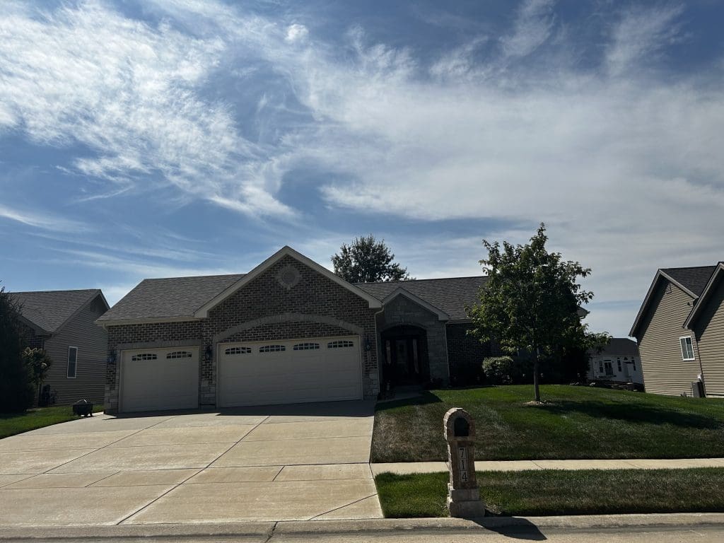 St. Louis single-story brick home with pristine roof, siding, and gutters, three-car garage, and tidy lawn on a sunny day.
