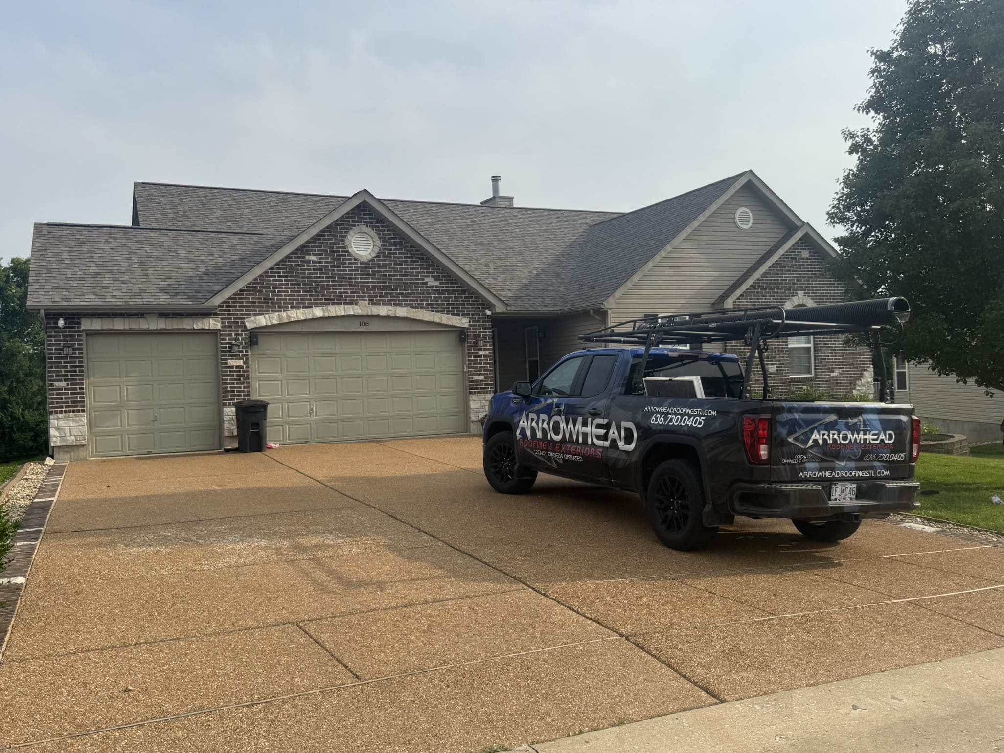 Arrowhead Roofing truck parked at a brick and siding home in Greater St. Louis, ready for roofing or gutter service.