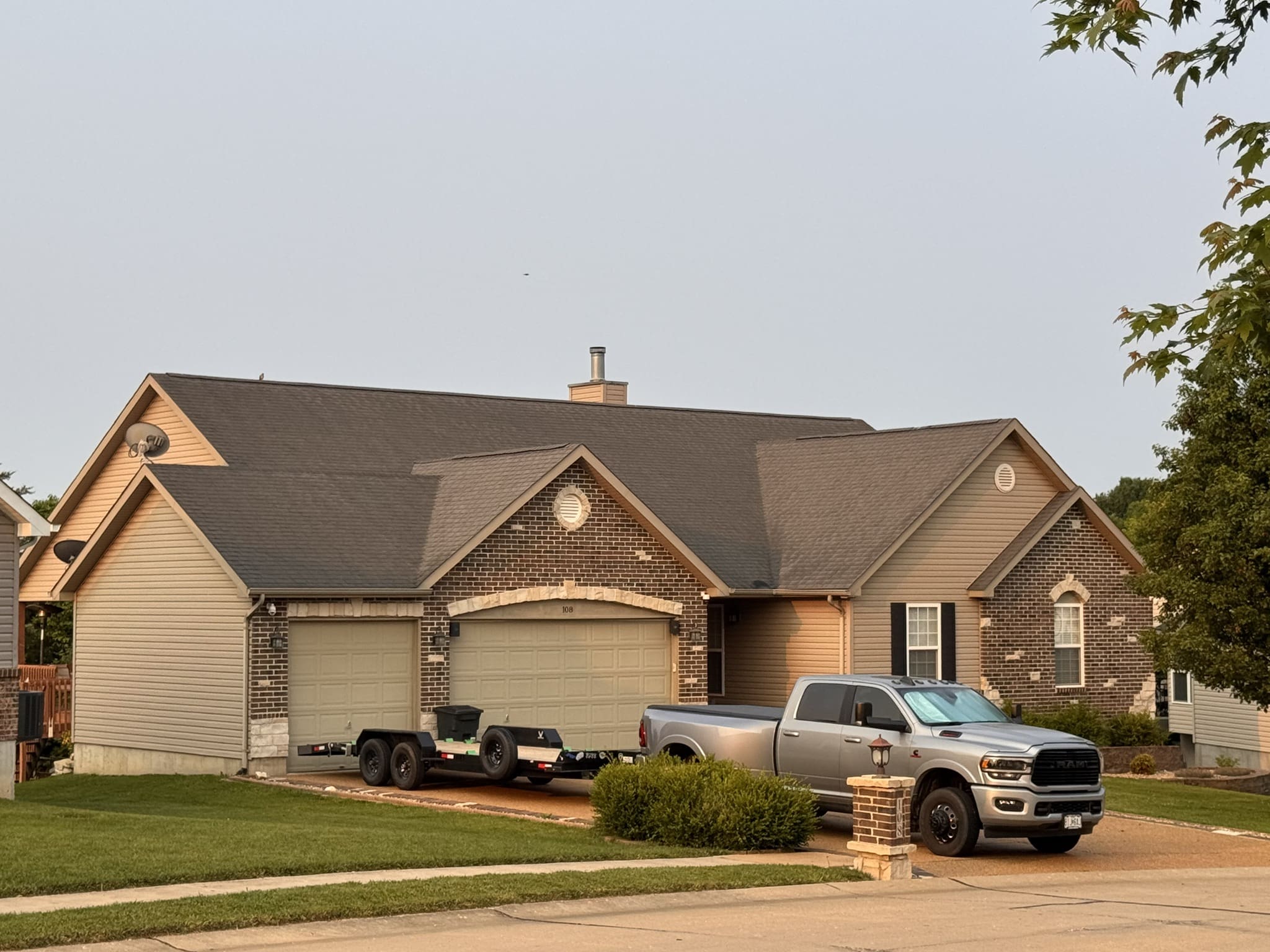 St. Louis single-story home with brick and siding, two-car garage, silver pickup, ideal for roofing or gutter services.